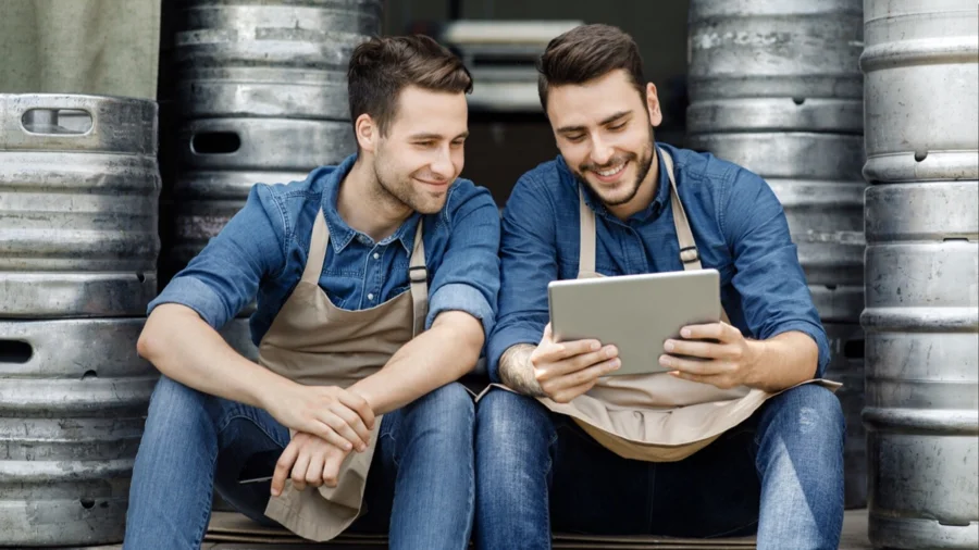 Zwei junge Gastronomen mit Tablet in einem Lager voller Bierfässer  | Drinkport