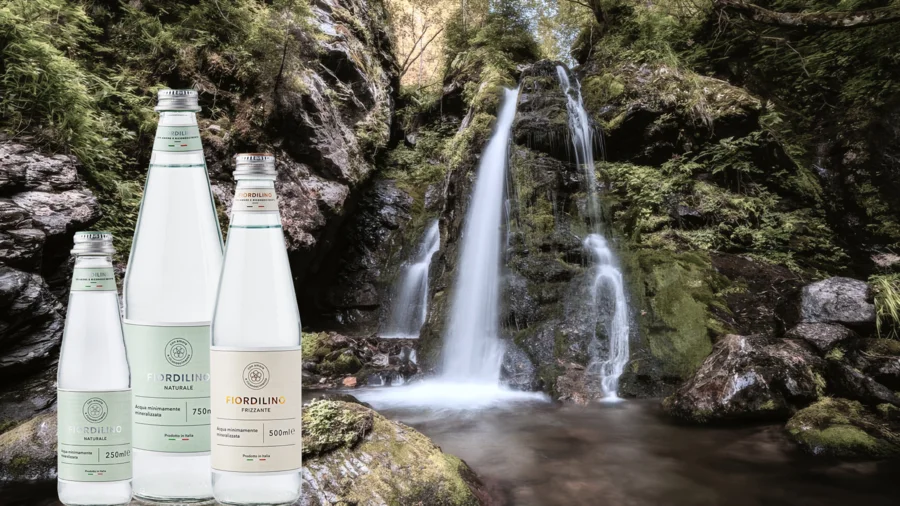 Acqua Fiordilino-Flaschen vor Wasserfall im Trentino | Drinkport