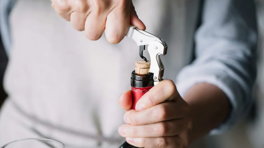 Mann öffnet Weinflasche in Gastro-Schulung der Wein Compagny | Drinkport